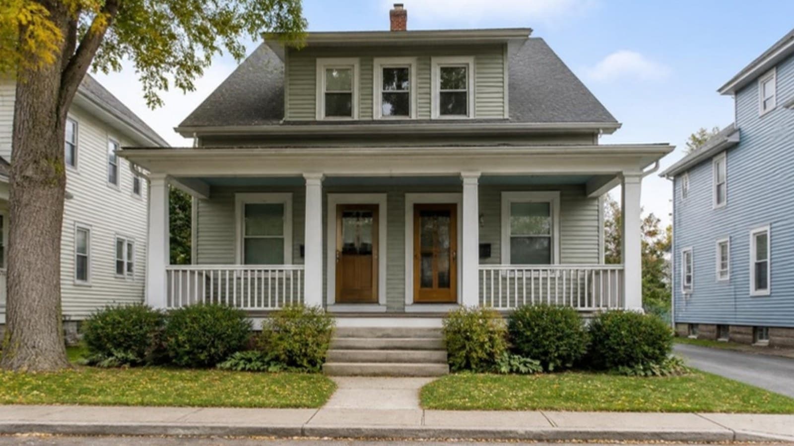 Two-unit house with separate front doors on a quiet residential street, for a guide to house hacking
